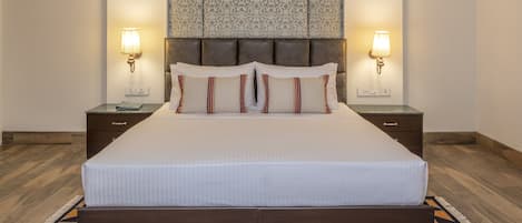 Una cama grande con cabecera de madera, dos lámparas de noche y un tapiz decorativo en la pared.