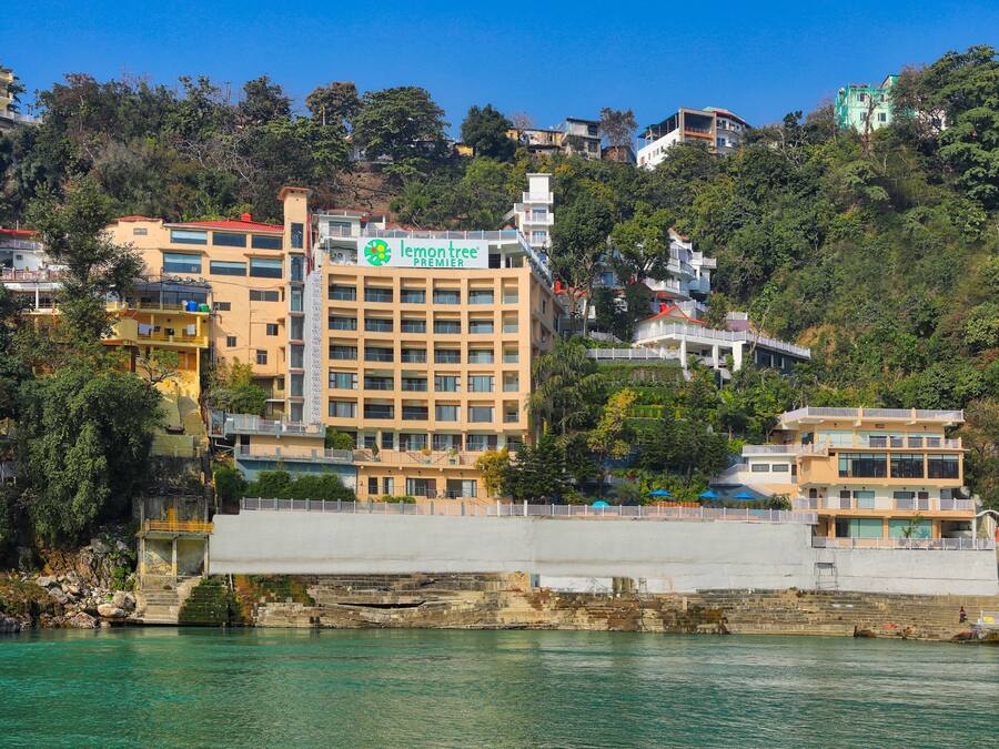 A multi-story hotel with a prominent 'lemon tree' sign, located near a waterfront with a rocky shoreline.