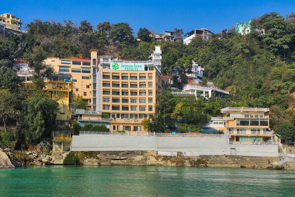 A multi-story hotel with a prominent 'lemon tree' sign, located near a waterfront with a rocky shoreline.