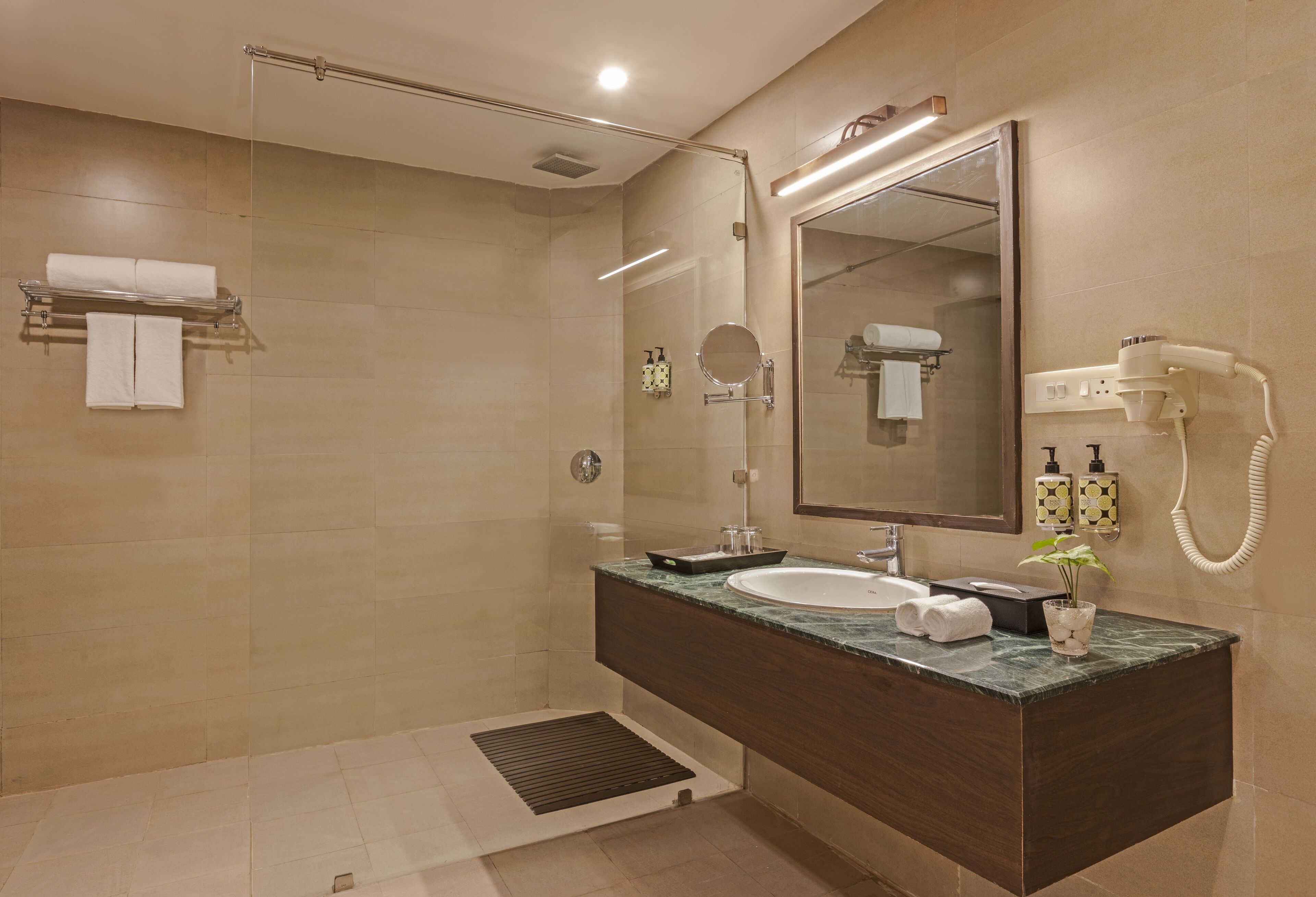 Un baño moderno con ducha, tocador y un espejo grande.
