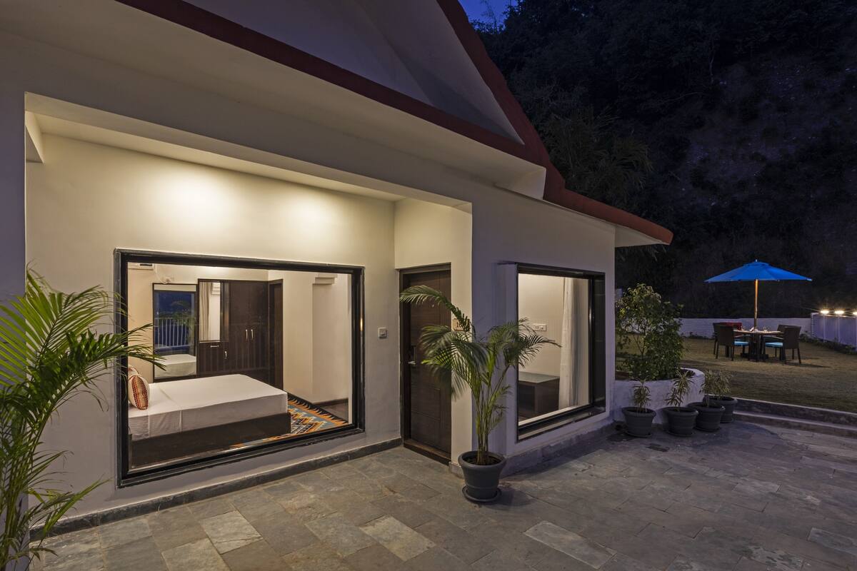 A modern house with a patio area, large windows, and potted plants.