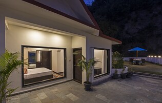 Una casa moderna con patio, ventanas amplias y plantas en macetas.