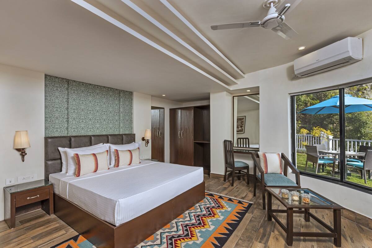 A modern hotel room with a large bed, a desk, and a view of the outdoors.