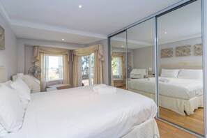 A hotel room with a large bed, a mirror, and a view of the balcony. - Apartment M311 - spacious and relaxed apartment! (Scarborough)