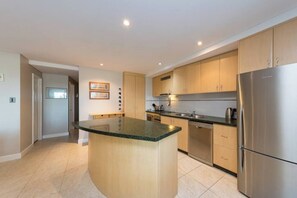 A modern kitchen with wooden cabinets, a stainless steel refrigerator, and a granite countertop island. - Apartment M311 - spacious and relaxed apartment! (Scarborough)