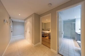 A hallway leading to a bedroom with a bed, a bathroom with a shower, and a toilet. - Apartment M311 - spacious and relaxed apartment! (Scarborough)