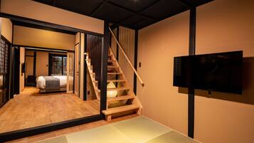 A modern interior with a wooden staircase, a bed, and a television mounted on the wall.