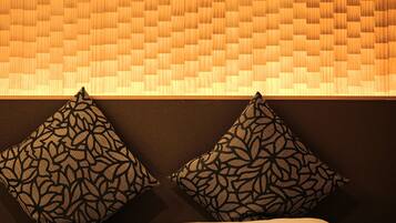 A bed with two patterned pillows and a woven headboard.
