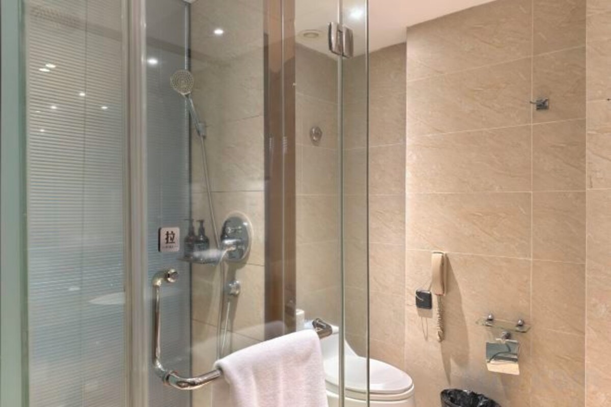 A modern bathroom with a glass-enclosed shower, a toilet, and a sink.