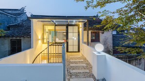 A traditional building with a modern extension featuring a glass door entrance, a staircase, and a satellite dish. - Floral Hotel Yi Shu Yu She Zhouzhuang (Suzhou)