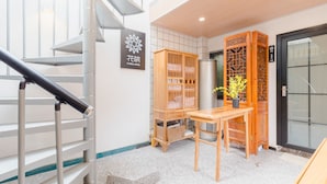 A hotel lobby with a staircase, a wooden cabinet with bedding, a table with a vase, and a traditional wooden screen. - Floral Hotel Yi Shu Yu She Zhouzhuang (Suzhou)