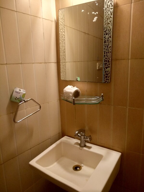A bathroom with a white sink, a mirror, and a towel rack. - Flavours Inn (Kolkata)