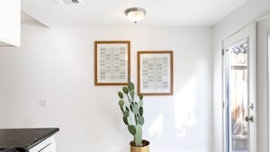 Une cuisine moderne et épurée, dotée d’un plan de travail en granit, d’un cactus en pot et d’œuvres d’art encadrées accrochées au mur.