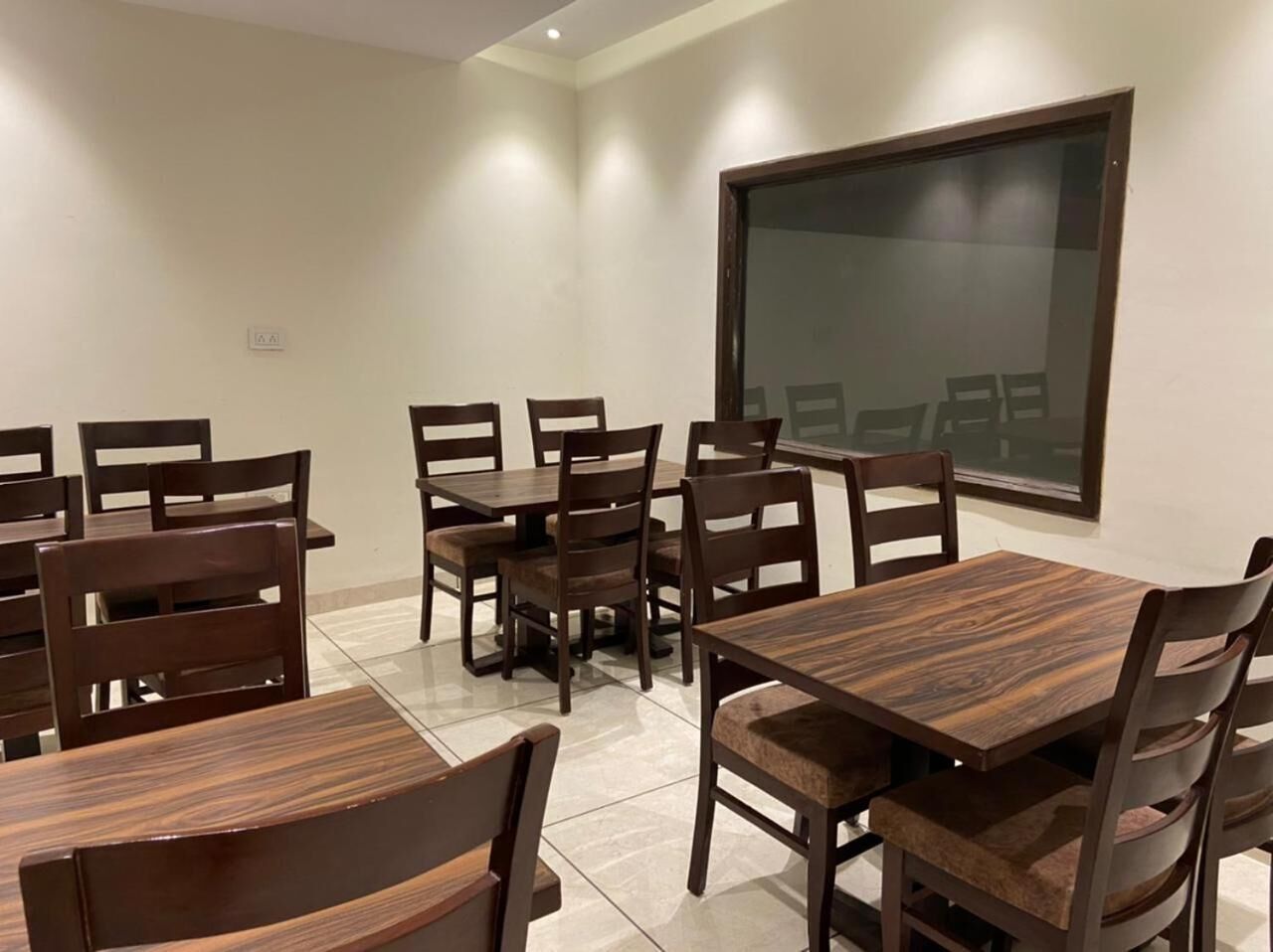 A conference room with multiple wooden tables and chairs, a large window, and a tiled floor.