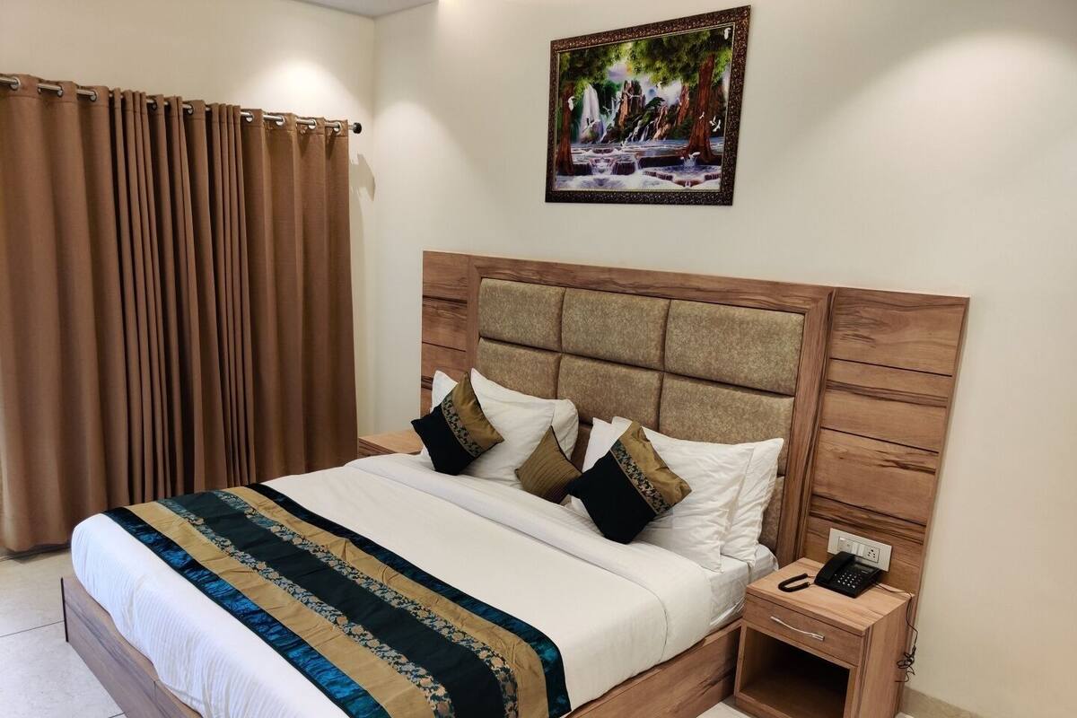 A neatly made bed with a striped blanket, a wooden headboard, and a bedside table with a phone.