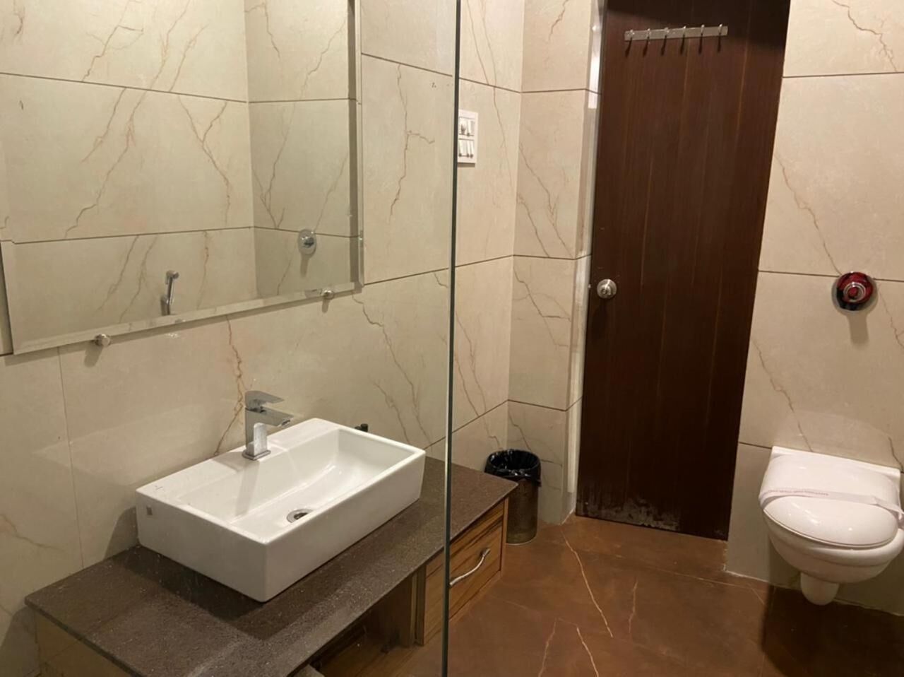 Une salle de bain avec un lavabo blanc, un miroir, une douche et des toilettes.