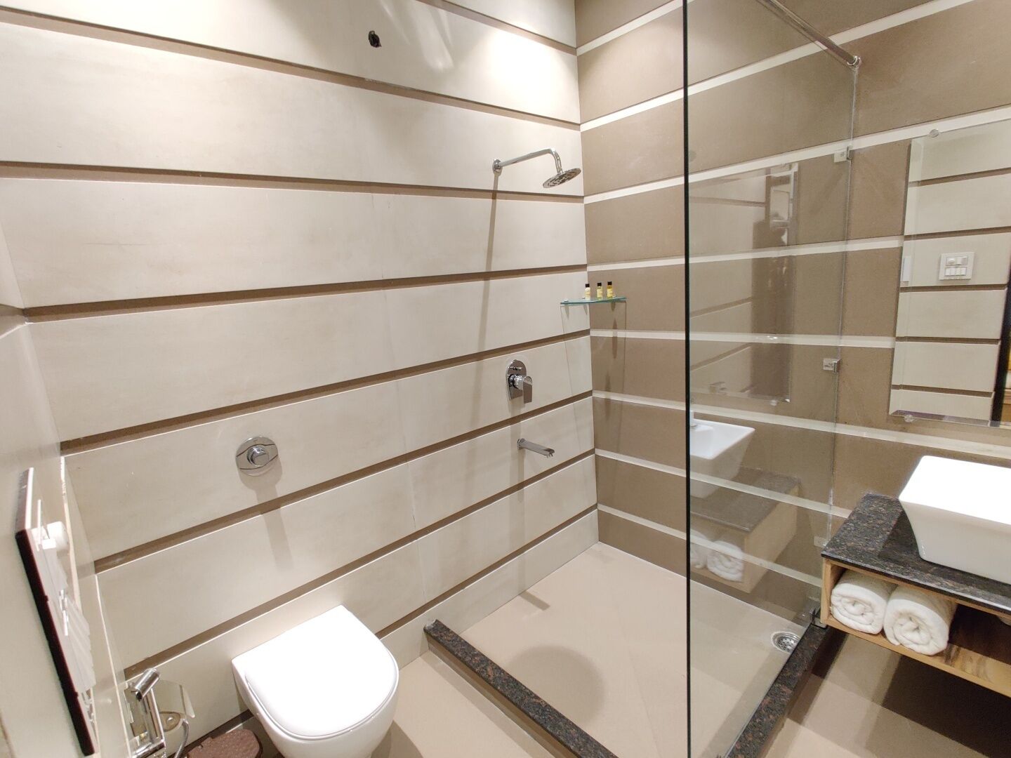 A modern bathroom with a glass shower enclosure, a white toilet, and a sink with a marble countertop.