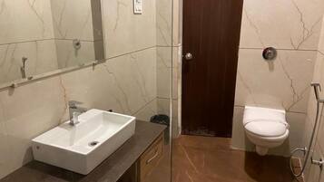 Casa de banho com lavatório branco, sanita e zona de duche.