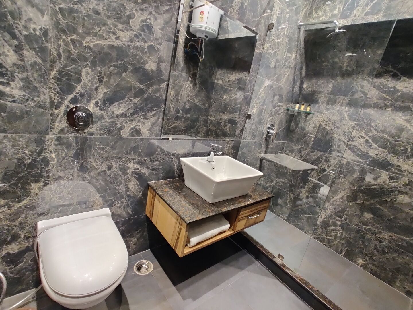 Un baño moderno con salpicadero de mármol, un lavabo blanco y un inodoro.