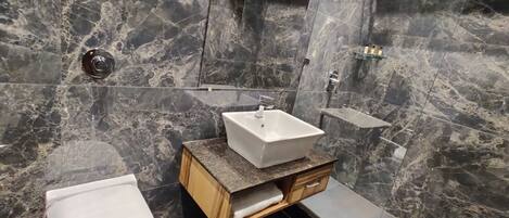Un baño moderno con salpicadero de mármol, un lavabo blanco y un inodoro.
