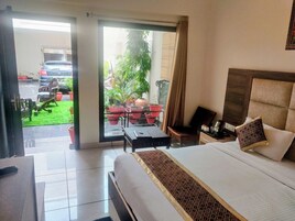 Habitación de hotel con cama, escritorio, silla, cafetera y vista al exterior.
