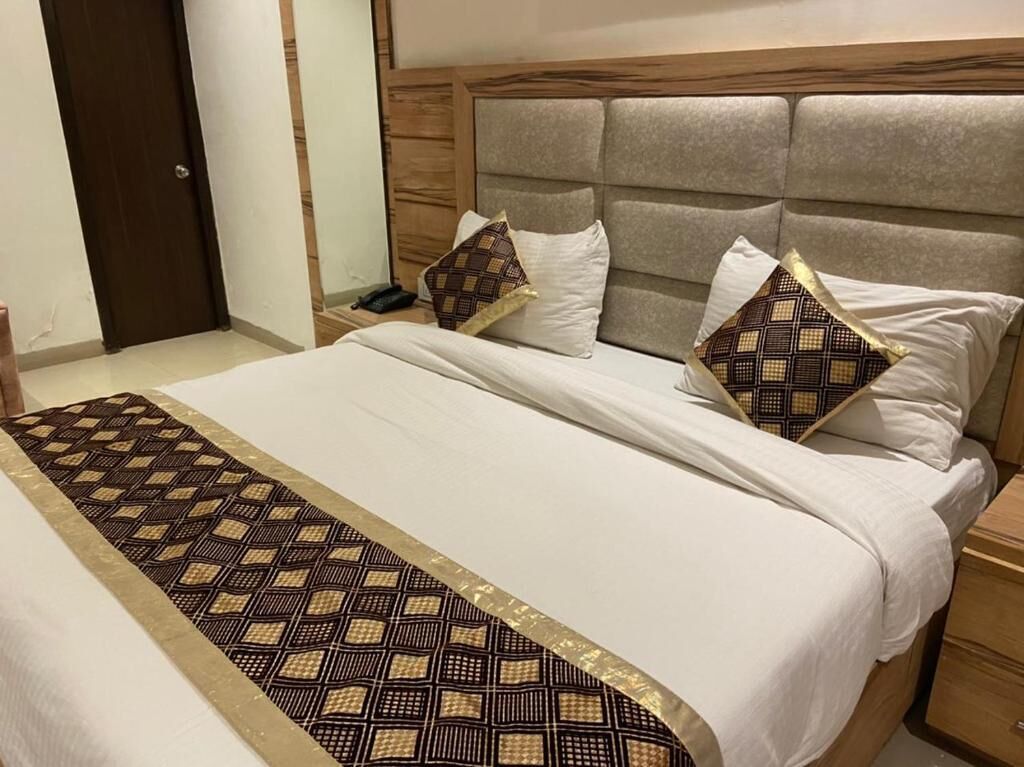 A neatly made bed with a patterned runner, a wooden headboard, and two decorative pillows.