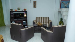 Una sala de estar con un sofá, un televisor y una mesita de centro.