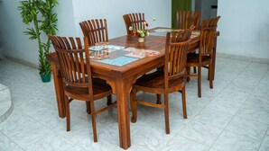Una mesa de madera para comer con seis sillas, un camino de mesa decorativo y una planta en maceta.