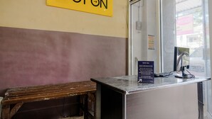 A reception desk with a 'SPOT ON' sign above it, a bench to the left, and a window to the right. - SPOT ON 2387 Bukit Cemara Tidar Family (Malang)