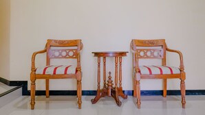Dos sillas de madera con asientos y respaldos acolchados, una mesita de madera y un objeto decorativo sobre la mesa.