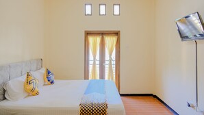 Una habitación de hotel con cama, televisión y ventana con cortinas.