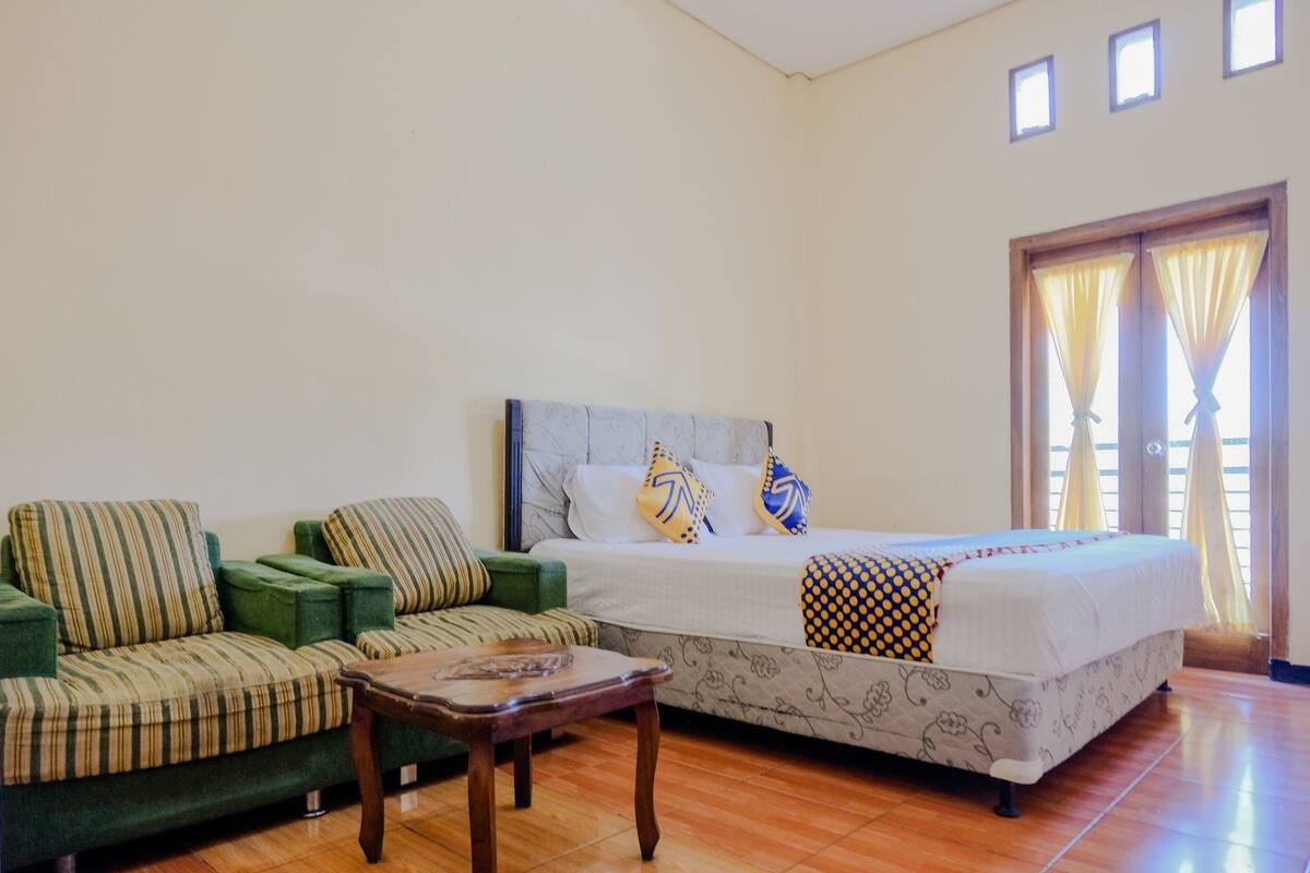 Un dormitorio con cama, sofá y una mesita.