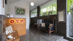 Un espace d’accueil avec un bureau en bois, un canapé et un mur en pierre.