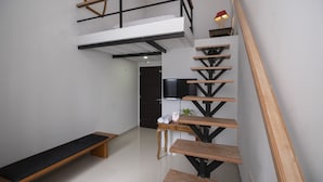 Un intérieur moderne avec un escalier, un banc et un téléviseur à écran plat.