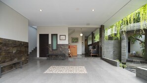 Un hall d’entrée spacieux avec un mur en pierre, un tapis à motifs et un comptoir d’accueil.