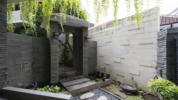 Une cour avec un chemin en pierre, un petit jardin agrémenté de plantes et un évier extérieur rustique.