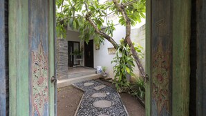 Un chemin menant à l’entrée d’une maison, avec des portes décoratives et un petit jardin.