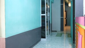 A hallway with a glass door leading to a room, tiled floor, and a colorful wall. - OYO 2389 Kostel 99 (Pangkalpinang)