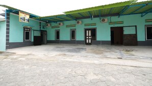 A building with a tiled floor and a green roof. There are multiple doors and windows, and a sign on the left side. - OYO 2389 Kostel 99 (Pangkalpinang)