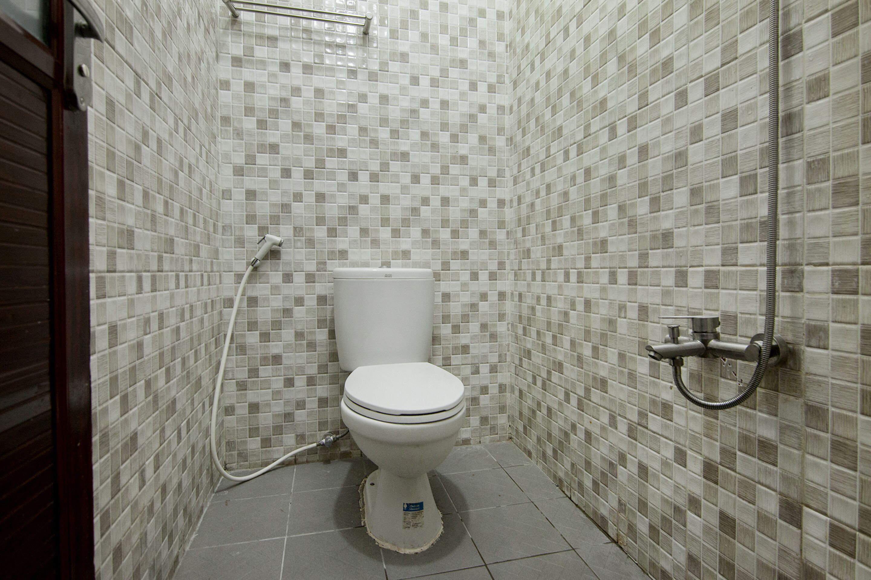 Un baño pequeño con inodoro, ducha y paredes de azulejos.