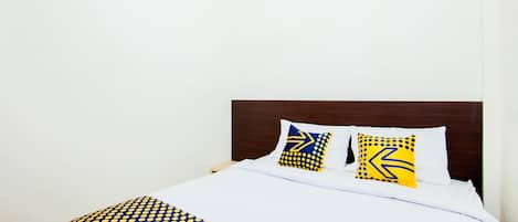 A neatly made bed with a blue and yellow patterned bedspread and two pillows with similar designs.