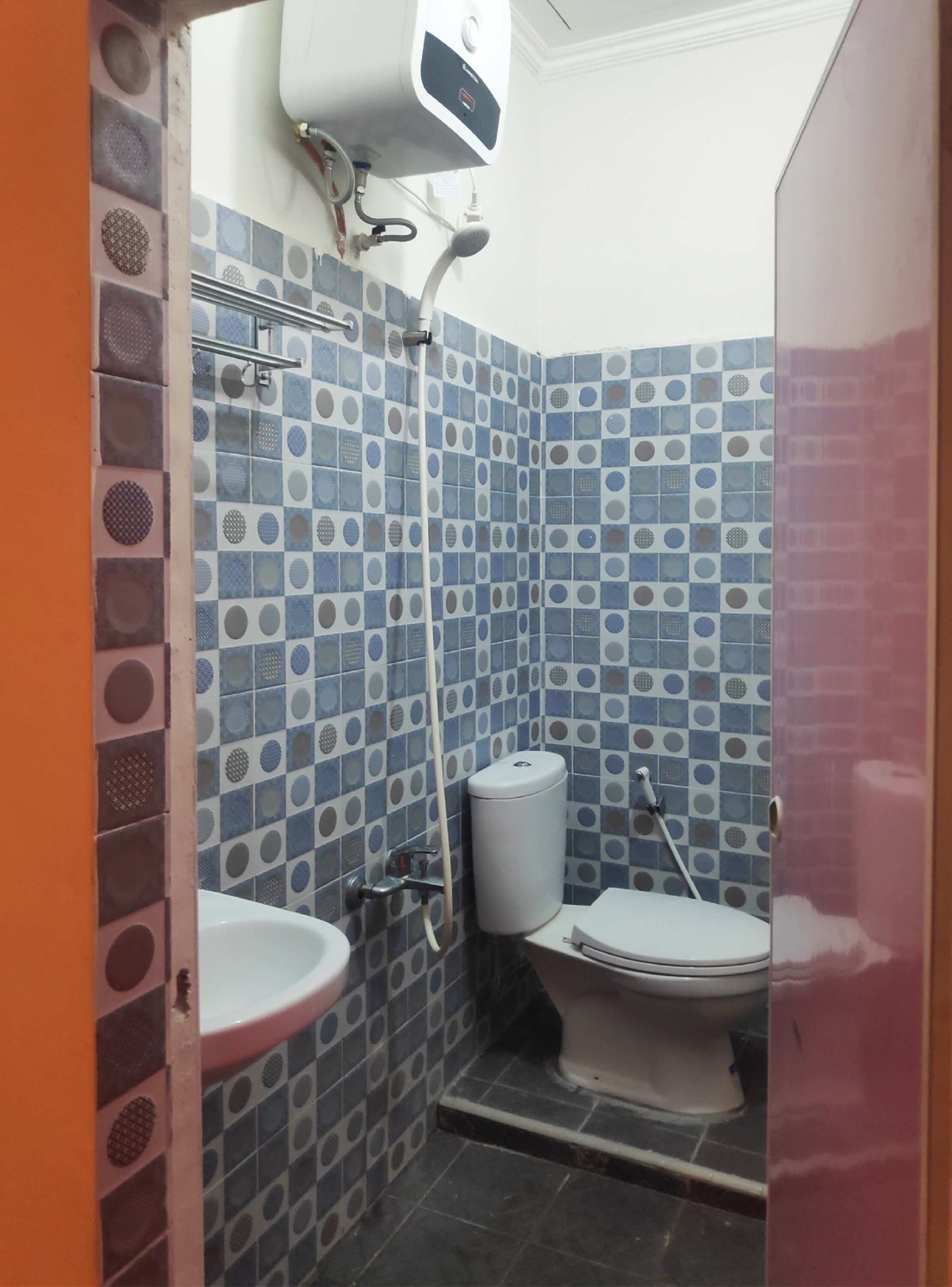 A bathroom with blue and white patterned tiles, a white toilet, and a white sink.