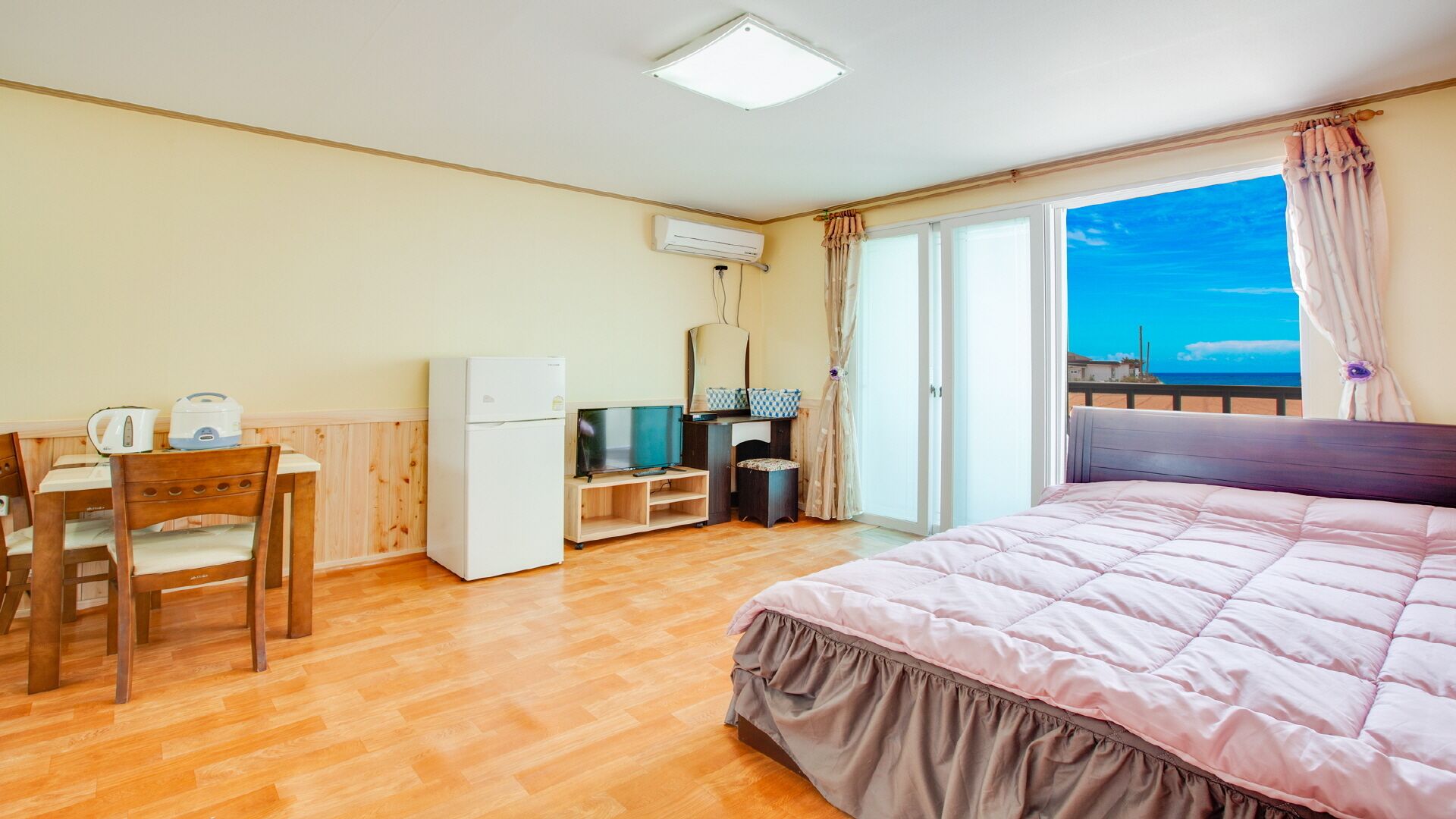 Ein Schlafzimmer mit einem Bett, einem Schreibtisch mit Stuhl, einem Fernseher und einer Klimaanlage.