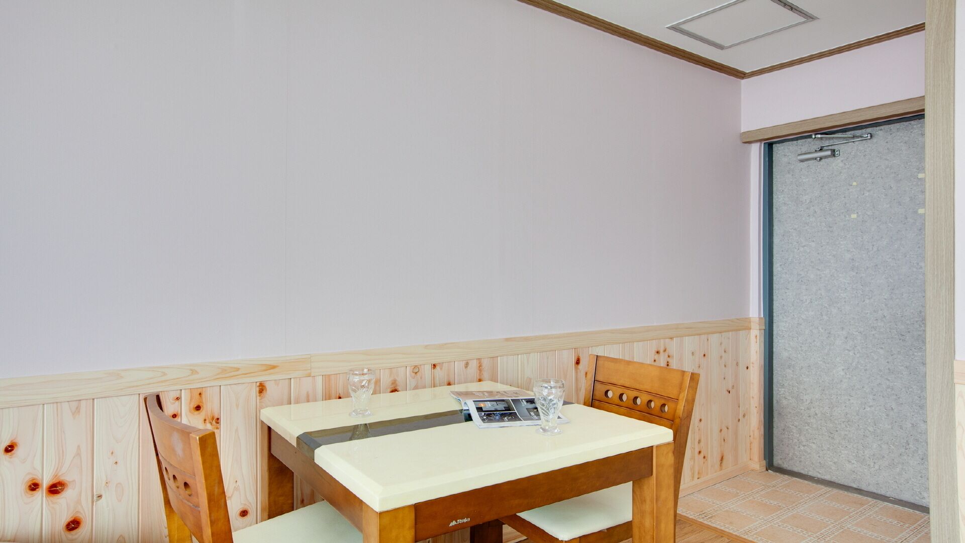 A small room with a wooden table and chairs, a door, and a tiled floor.