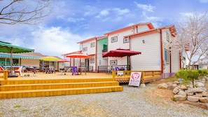 A restaurant with outdoor seating, a wooden deck, and a signboard. - Vellise Pension (Taean)