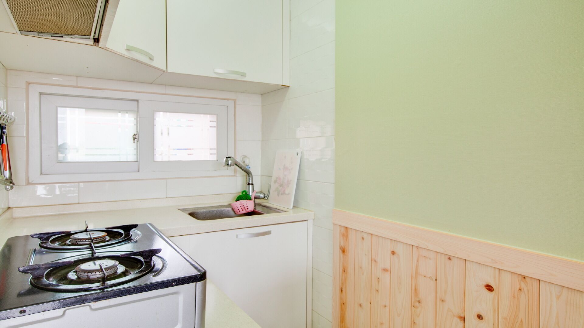 A compact kitchen with a stove, sink, and window.