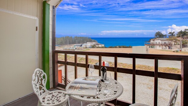 A balcony with a table, chairs, and a bottle of wine. - Vellise Pension (Taean)