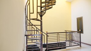 A spiral staircase with metal railings and a handrail, leading to a landing with a door. - SPOT ON 2431 Tf Homestay (Caruban)