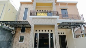 A multi-story hotel with a 'SPOT ON' sign, a balcony, and a gated entrance. - SPOT ON 2431 Tf Homestay (Caruban)
