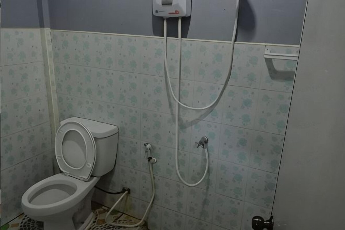 A bathroom with a toilet, a shower, and a tiled wall.